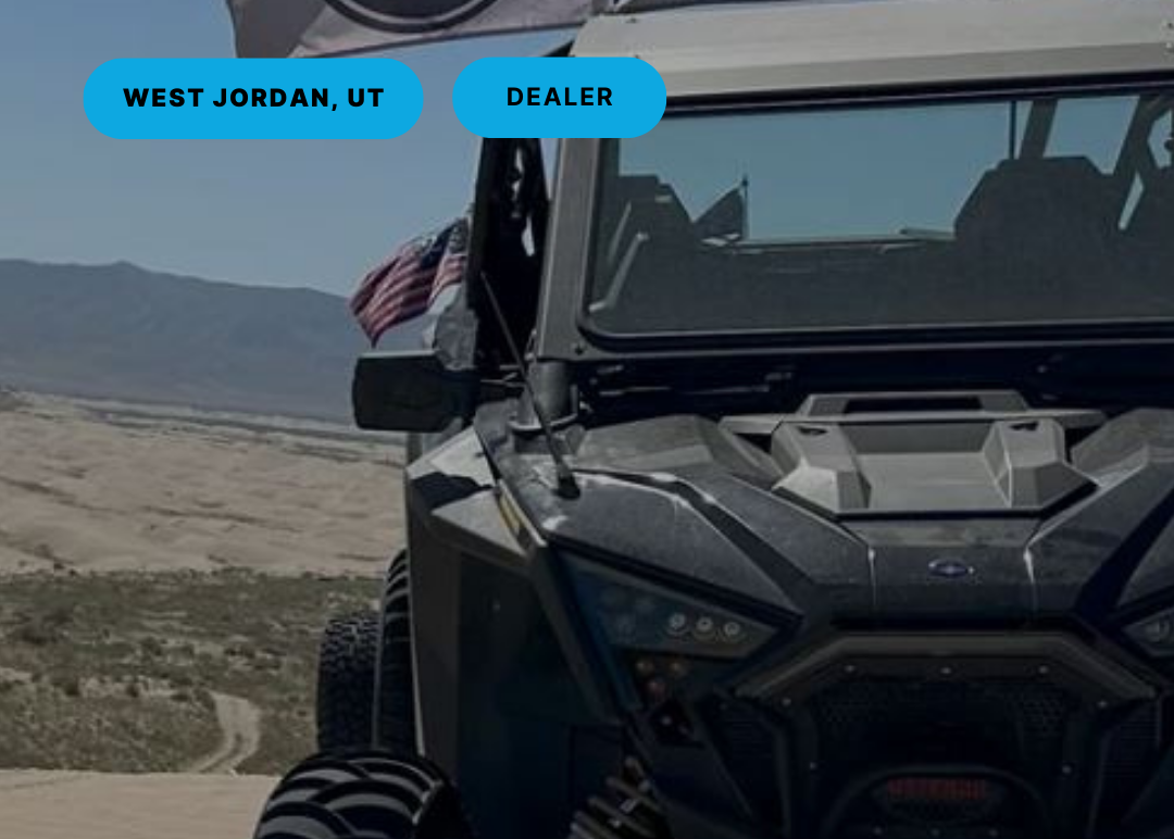 Off-road vehicle on a desert road with 'West Jordan, UT Dealer' text overlay.