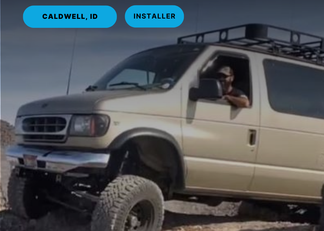 Beige van with a roof rack on a dirt road, with text indicating location and ownership.