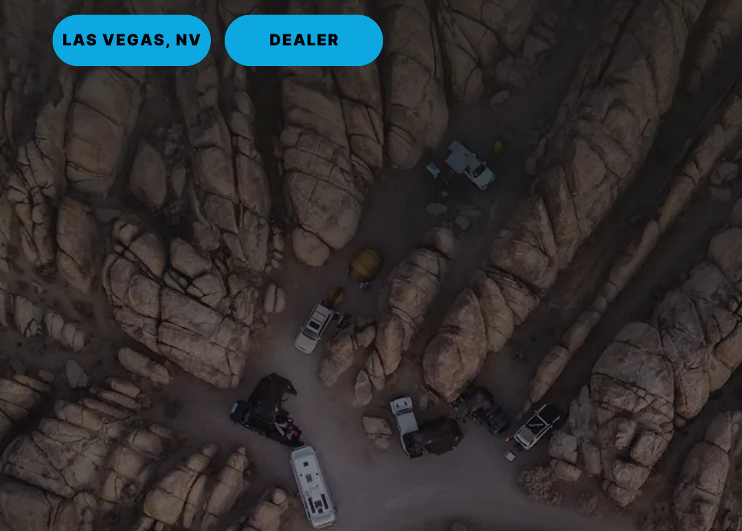 Aerial view of a desert landscape with rocky formations and vehicles, labeled 'Las Vegas, NV Dealer'.